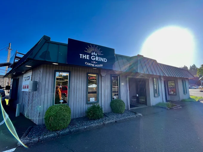 Exterior of The Grind Coffee House showing the navy sign and storefront on a sunny day in Estacada, Oregon